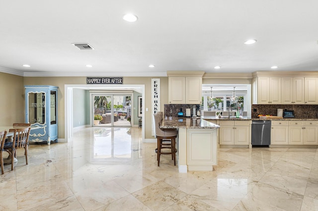 kitchen with marble finish floor, cream cabinets, stone countertops, and decorative backsplash