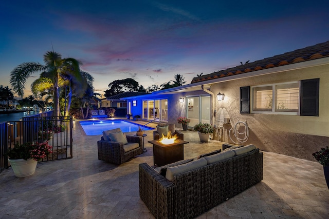 view of swimming pool with a fenced in pool, an outdoor living space with a fire pit, and a patio