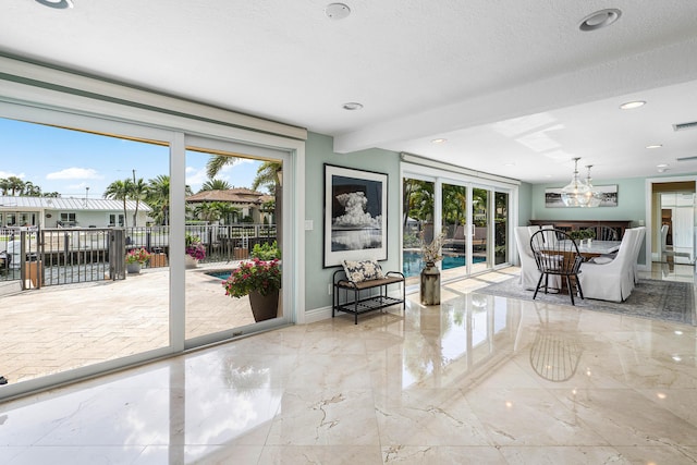 interior space with a healthy amount of sunlight, marble finish floor, baseboards, and a notable chandelier