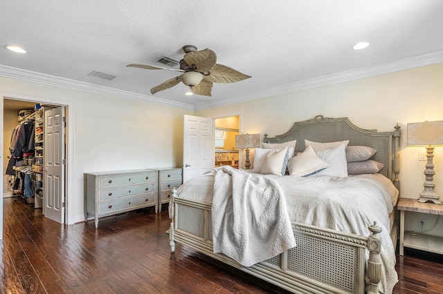 bedroom with visible vents, a spacious closet, ornamental molding, ceiling fan, and hardwood / wood-style flooring