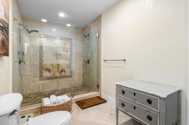 bathroom with toilet, a stall shower, baseboards, and marble finish floor