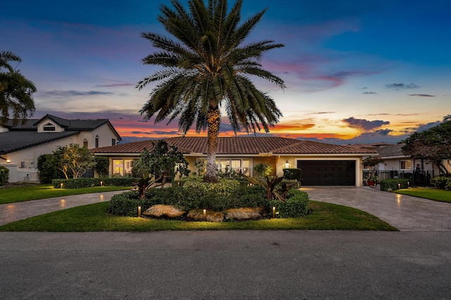 view of front of property with decorative driveway, an attached garage, a tile roof, and stucco siding