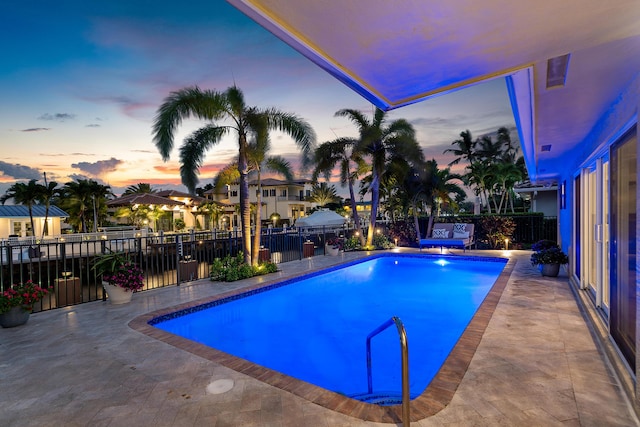 pool at dusk featuring a patio area, fence, and a fenced in pool