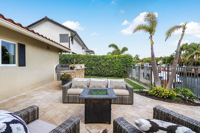 view of patio / terrace featuring a fenced backyard, area for grilling, exterior kitchen, and an outdoor living space with a fire pit