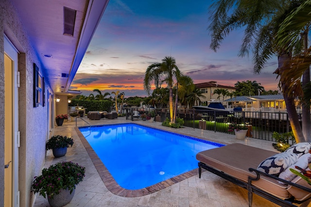 pool at dusk featuring a fenced in pool, outdoor lounge area, a patio, and fence