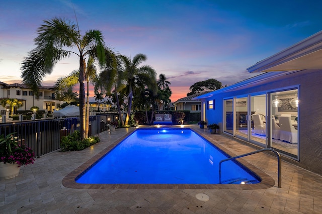 pool at dusk featuring a patio, fence, and a fenced in pool