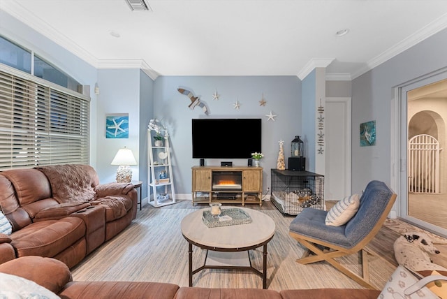 living room with baseboards, wood finished floors, visible vents, and ornamental molding