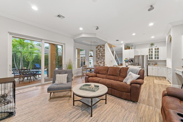 living area with crown molding, recessed lighting, light wood-style floors, and visible vents