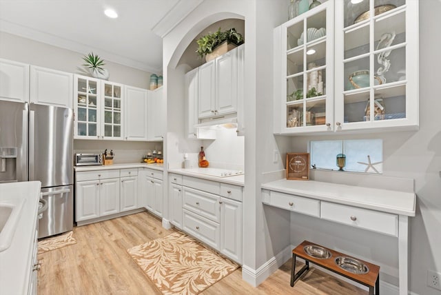 kitchen featuring light wood finished floors, stainless steel refrigerator with ice dispenser, under cabinet range hood, white cabinetry, and crown molding