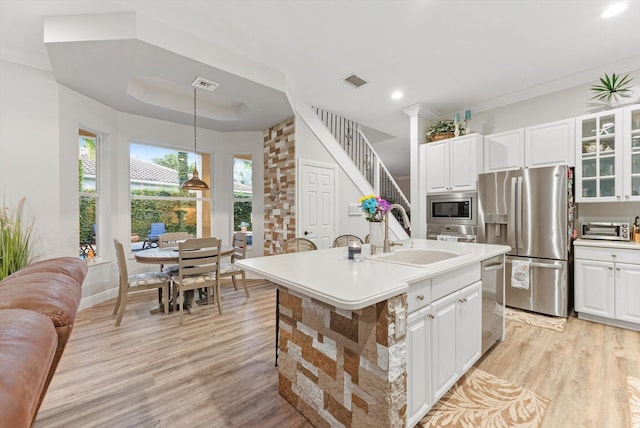 kitchen with visible vents, light wood-style flooring, white cabinets, stainless steel appliances, and a sink