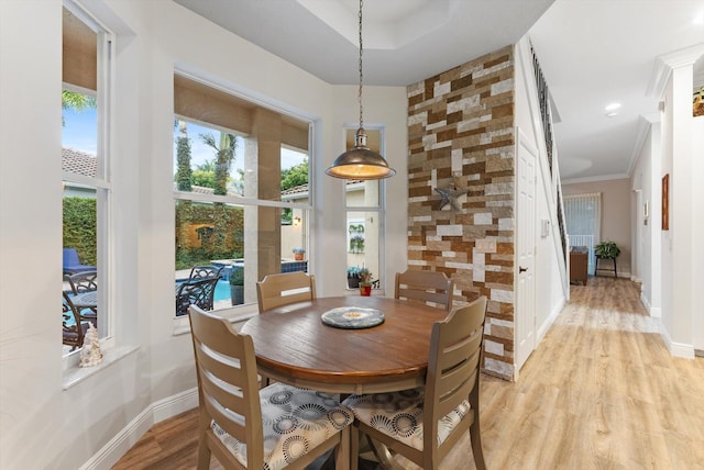 dining area with baseboards, ornamental molding, and light wood finished floors