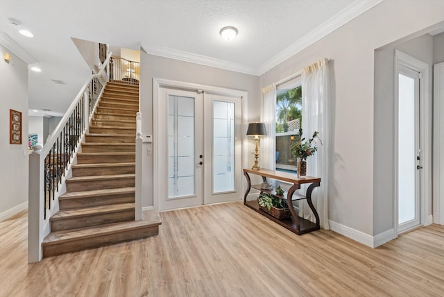 foyer entrance featuring baseboards, wood finished floors, stairs, and crown molding