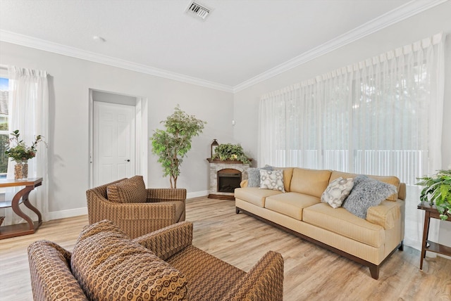 living area featuring visible vents, ornamental molding, and light wood finished floors