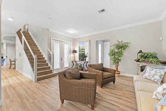 living room with light wood finished floors, visible vents, stairs, and ornamental molding