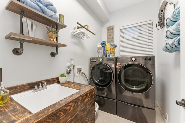 clothes washing area with washer and clothes dryer, laundry area, and a sink