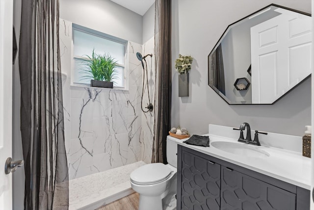 bathroom featuring vanity, wood finished floors, a shower stall, and toilet