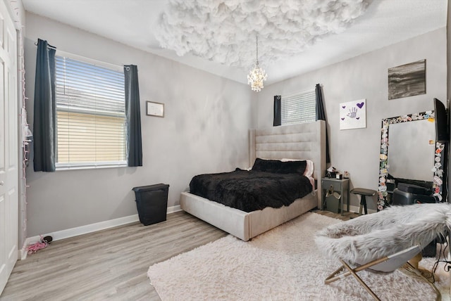 bedroom featuring wood finished floors, baseboards, and a chandelier