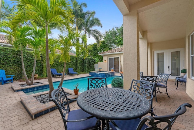 view of pool featuring outdoor dining space, a patio area, french doors, and a pool with connected hot tub