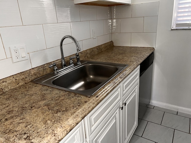 kitchen with tasteful backsplash, stainless steel dishwasher, white cabinetry, a sink, and baseboards