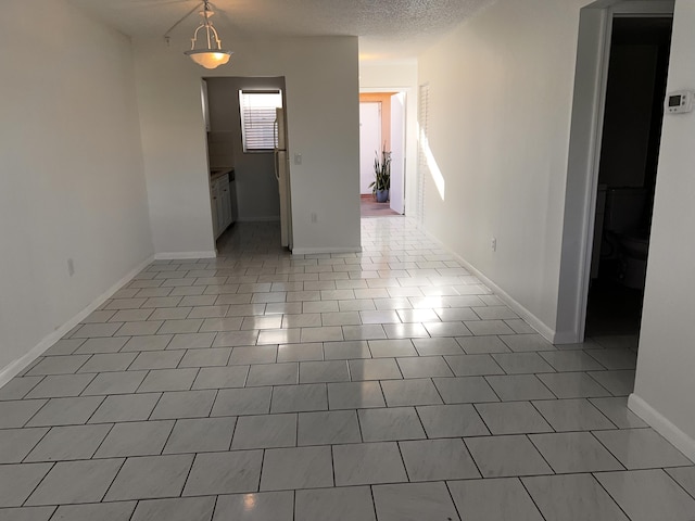 spare room featuring baseboards, a textured ceiling, and tile patterned floors