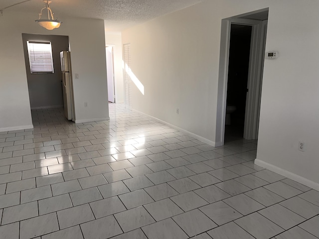 spare room with a textured ceiling, baseboards, and tile patterned floors