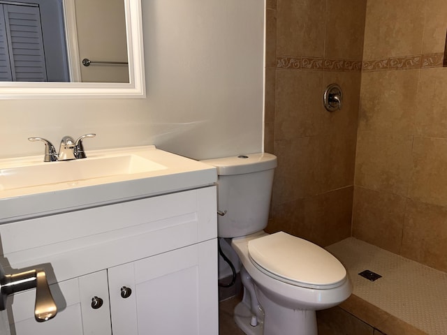 full bath with a tile shower, vanity, and toilet