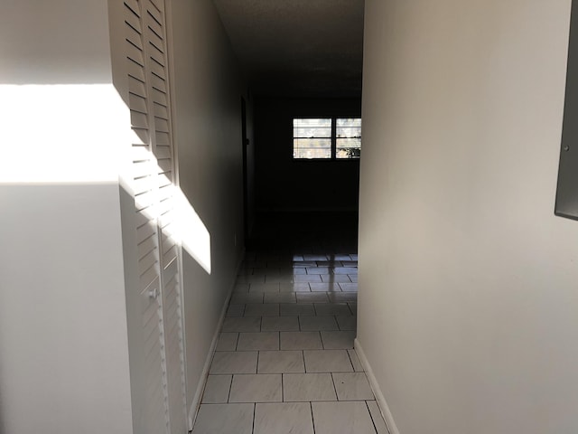 hallway featuring tile patterned flooring and baseboards