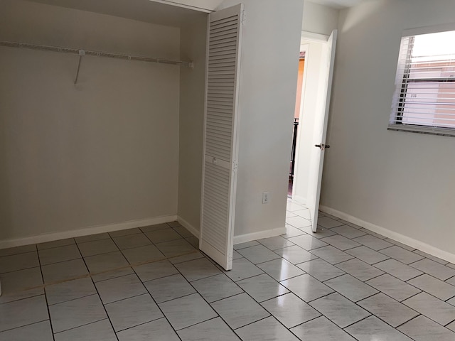 unfurnished bedroom with light tile patterned floors, baseboards, and a closet