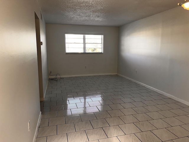 spare room with a textured ceiling and baseboards