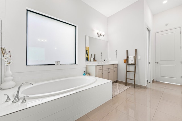 bathroom featuring tile patterned floors, vanity, baseboards, and a bath