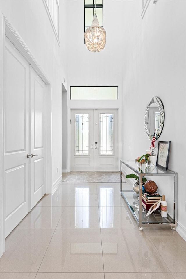 entrance foyer featuring a towering ceiling, baseboards, and french doors