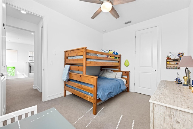 carpeted bedroom featuring a ceiling fan, visible vents, and baseboards