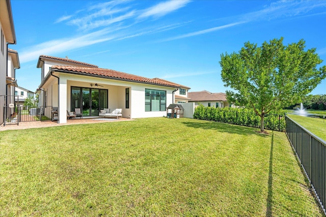 rear view of house with a patio area, ceiling fan, a lawn, and a fenced backyard