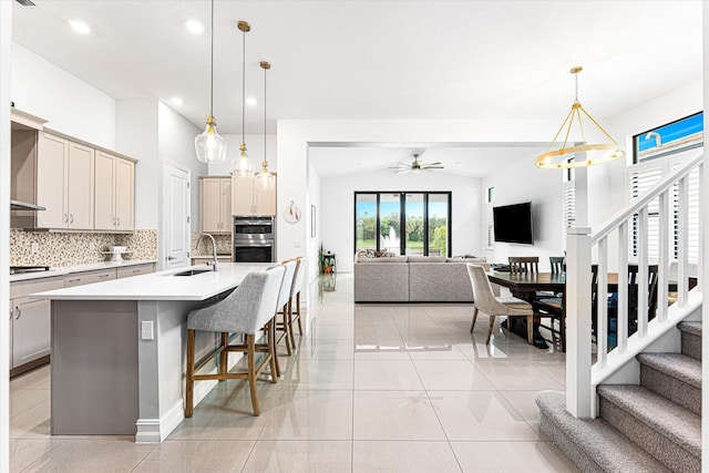 kitchen with cooktop, light countertops, decorative backsplash, open floor plan, and a sink