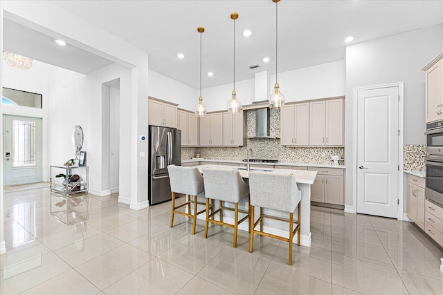 kitchen featuring decorative backsplash, stainless steel appliances, light countertops, wall chimney range hood, and a kitchen bar