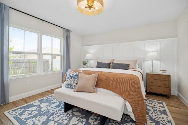 bedroom featuring light wood-style flooring, a notable chandelier, and baseboards