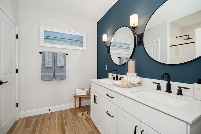 bathroom with a sink, baseboards, double vanity, and wood tiled floor