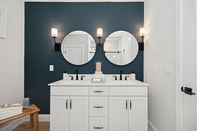 full bath with double vanity, baseboards, and a sink