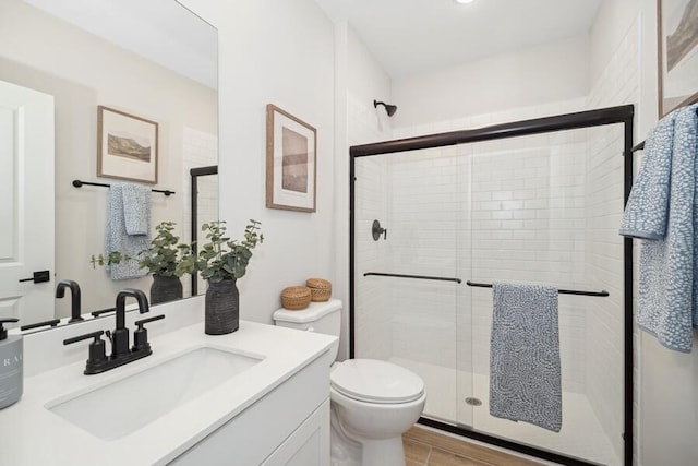 bathroom featuring a stall shower, toilet, and vanity