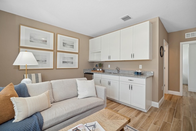 living area with visible vents, baseboards, and wood finish floors