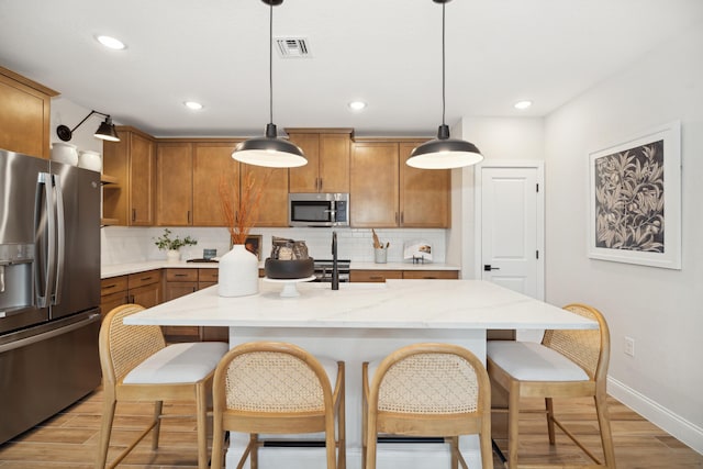 kitchen with brown cabinetry, visible vents, backsplash, and appliances with stainless steel finishes