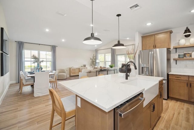 kitchen featuring visible vents, backsplash, wood tiled floor, stainless steel appliances, and a sink