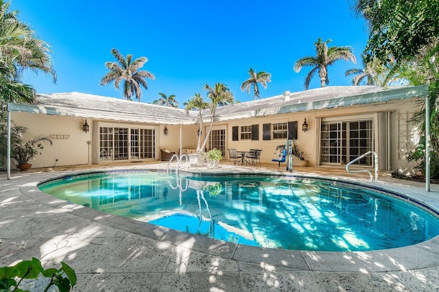 rear view of house featuring a patio area, stucco siding, and an outdoor pool