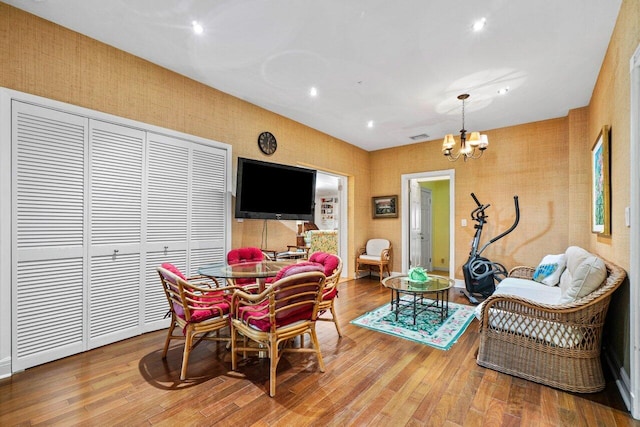 dining room with a chandelier, visible vents, wallpapered walls, and wood finished floors