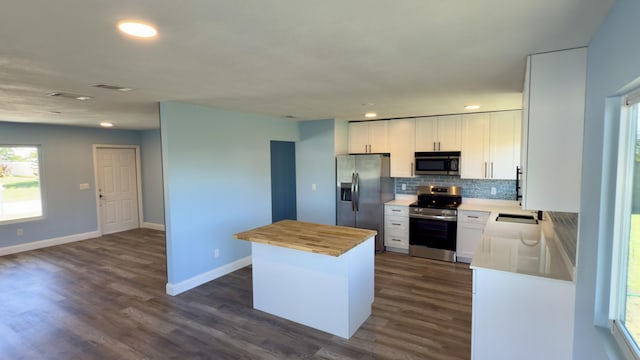 kitchen featuring dark wood-style flooring, a kitchen island, wooden counters, appliances with stainless steel finishes, and decorative backsplash