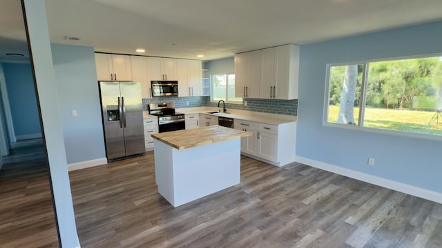 kitchen featuring stainless steel appliances, dark wood-style flooring, a sink, and backsplash