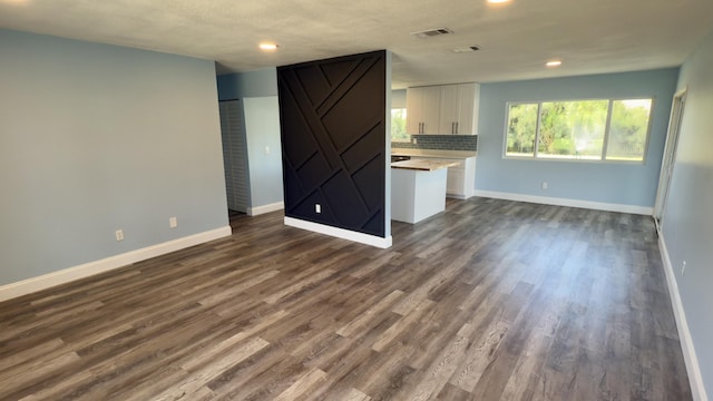 unfurnished living room featuring recessed lighting, visible vents, dark wood finished floors, and baseboards