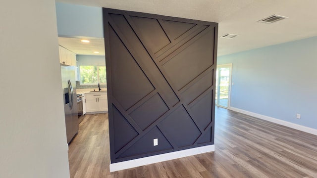 interior details with visible vents, wood finished floors, a sink, and stainless steel fridge with ice dispenser