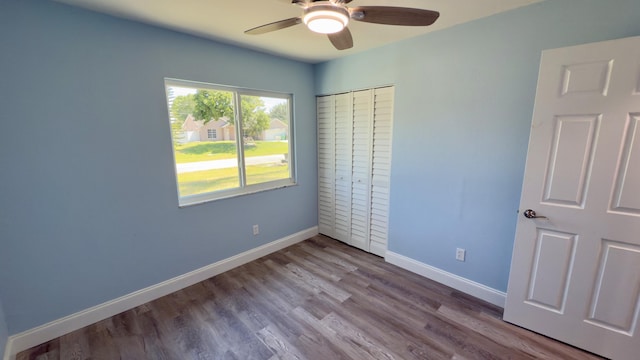 unfurnished bedroom featuring a ceiling fan, a closet, baseboards, and wood finished floors