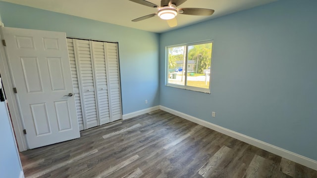 unfurnished bedroom with dark wood-style floors, a closet, ceiling fan, and baseboards